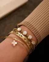 Pulsera rígida dorada con cuatro piedras redondas de nácar engarzadas.