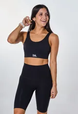 Conjunto deportivo negro compuesto por un top con logo y calza ciclista de tiro alto.