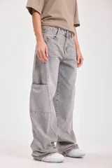 Pantalón de jean gris, corte wide leg, con bolsillos laterales y pañuelo estampado atado a la cintura.