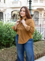 Camisa color marrón de corte clásico, con cuello y mangas largas. Tiene un bolsillo decorativo discreto y botones al tono.