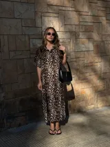 Vestido camisero de muselina color negro, de largo midi, con cuello clásico, manga corta y cierre frontal con botones.