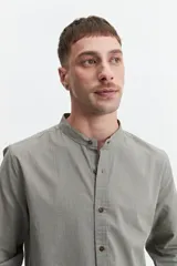 Camisa azul de manga larga con cuello mao y cartera abotonada.