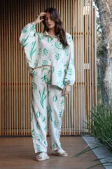 Conjunto de camisa de manga larga y pantalón largo, ambos con estampado abstracto en tonos rosa sobre fondo blanco. Camisa de corte oversized con cuello clásico y cierre frontal con botones. Pantalón con bolsillos laterales.