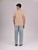 Remera beige de manga corta con cuello redondo y estampado frontal con texto "American" y dibujo de una moto.