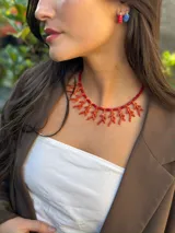 Collar corto con corales de resina color naranja y bastones de cuentas reconstituidas. Se cierra con cadena de acero quirúrgico y ganchito para regular el largo.