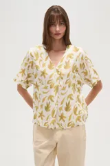 Blusa marrón con estampado de hojas color crema, cuello en V y mangas cortas. Corte holgado.