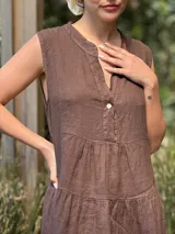 Vestido verde militar de lino, corte a la rodilla, sin mangas, con cuello mao y botones de nácar. Presenta varios cortes en su largo, aportando movimiento y un toque moderno a este diseño fresco y elegante.