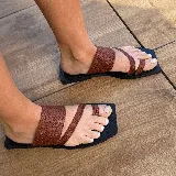 Sandalias planas de cuero color marrón con tiras cruzadas y base cuadrada negra.