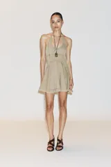 Vestido corto color beige con cuello halter y falda con godets.