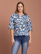 Blusa blanca de gasa marca Sioni, con cuello a la base y escote en V. Tiene abertura central con botones y mangas 3/4 con terminación fruncida.