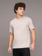 Remera color beige de algodón regenerativo con cuello redondo, mangas cortas y logo CK bordado en el pecho. Presenta un diseño de paisaje gráfico en el frente.