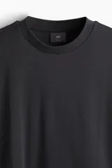 Remera negra de algodón pesado, corte holgado, con cuello redondo ribeteado, hombros caídos y bajo recto.