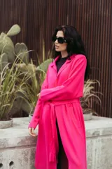 Saco largo color fucsia con cuello solapa, bolsillos laterales y lazo para atar en la cintura.