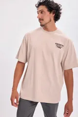 Remera color beige de corte oversize con estampa en la espalda con la frase "Trust the process".