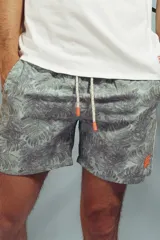 Short de baño con estampado de hojas en tonos grises y celestes, con cordón ajustable en la cintura y detalle de franja lateral con rayas rojas, blancas y negras.