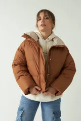 Campera puffer color marrón con cuello alto, corte cropped a la cadera, cierre metálico y botones.