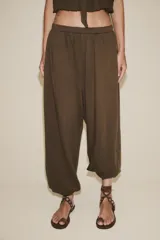 Pantalón bombacho color marrón de felpa de algodón, con cintura elástica, tiro alto, bolsillos laterales y puños elásticos en los tobillos.