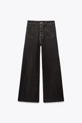 Pantalón de jean negro de tiro alto y corte wide leg, con bolsillos delanteros y traseros tipo parche. Cierre frontal con cremallera y botón metálico.
