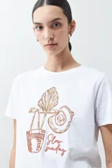 Remera blanca de algodón con estampa de motivos playeros en tonos marrones.