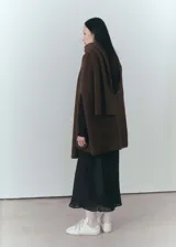 Abrigo marrón de tejido de punto de canalé con cuello bufanda, cierre de botones en la parte delantera y diseño recto sin mangas.