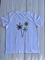 Remera blanca con estampado de palmeras y sol en la espalda.