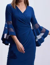 Vestido de noche RM Richards en seda fría color azul. Presenta escote en V cruzado, detalle de broche con brillos en el lateral y mangas amplias con apliques de microtul.