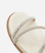 Sandalia plana mule color crema con punta redonda y tiras finas con brillos.