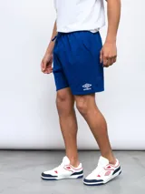 Bermuda deportiva azul rey de felpa, con cintura elástica y cordón de ajuste. Presenta el logo Umbro bordado en blanco en la pierna izquierda.