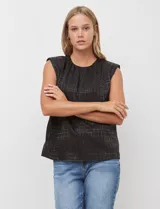 Blusa de gasa color beige con textura labrada, sin mangas, con hombreras internas y abertura en la espalda con botón.