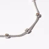 Pulsera plateada de cadena fina con cuentas cúbicas.