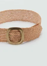 Cinturón ancho color beige, tejido en fibra natural con diseño trenzado y hebilla ovalada de metal color dorado.