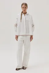 Camisa blanca de mangas largas abullonadas con bordados combinados y guardas, además de delicados bordados en el cuello y el bajo.