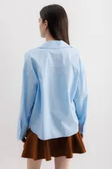 Camisa blanca de algodón con cuello clásico, mangas largas con puños abotonados y bolsillo de parche en el frente.