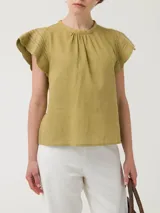 Blusa color verde oliva de algodón orgánico y ramie, con cuello redondo, mangas cortas con detalle de crochet y cierre con botón en la espalda.