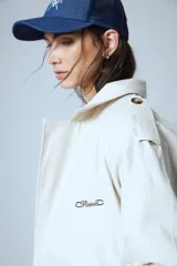 Campera corta color beige confeccionada en gabardina con lazo para ajustar en cintura, botones de pasta en charreteras y chapa RENÉE cursiva cosida a mano en el delantero.