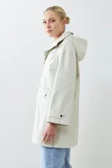 Campera impermeable gris claro con capucha plegable y bolsillos laterales.