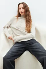 Polera de tejido de punto color beige, con cuello alto y mangas largas.