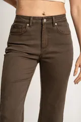 Pantalón jean marrón de corte flare, tiro medio y terminación desflecada.