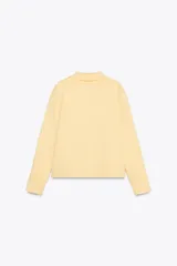 Chaqueta de punto color amarillo pálido, con cuello solapa y manga larga. Tiene bolsillos delanteros de plastrón y cierre frontal con botones con forma de flor.