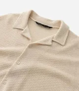 Camisa masculina de manga corta, color crema, con cuello bowling y calce boxy. El tejido presenta un efecto punto texturizado.