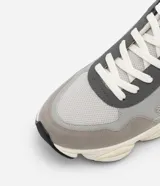 Championes dad sneaker grises con recortes en cuero sintético, cordones blancos y suela chunky de goma color crema.