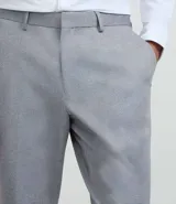 Pantalón de vestir gris claro con textura, de corte recto, con bolsillos laterales y traseros. Se ajusta a la cintura con cinturón de cuero negro.