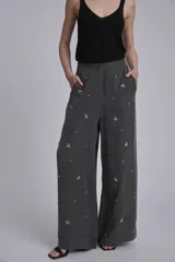 Pantalón palazzo gris con apliques de lentejuelas y mostacillas formando flores.