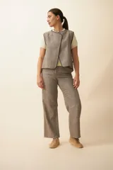 Chaleco marrón con solapas amplias y terminaciones envivadas. Diseño reversible y sin mangas.