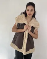 Chaleco marrón de cuero ecológico con interior de corderito color beige. Cierre con botones a presión.