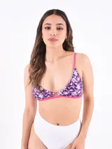 Top de bikini triangular con estampado floral en tonos azul, blanco y fucsia. Tiene tirantes finos fucsia y abertura en el centro del busto.