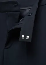 Pantalón de vestir azul marino, de corte recto, con bolsillos laterales y traseros. Se ajusta a la cintura con cinturón de cuero marrón.