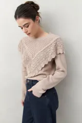Sweater color crema de punto liso con detalle de crochet en el escote y en forma de pico sobre el pecho.