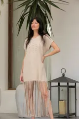 Vestido corto color beige de algodón, con cuello redondo, mangas cortas y flecos en el ruedo. Presenta tachas plateadas en el frente.