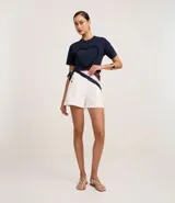 Remera azul marino de algodón con cuello redondo y mangas cortas. Presenta un aplique en forma de corazón con volados en el frente.